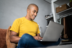 Man on his laptop sitting on the couch smiling